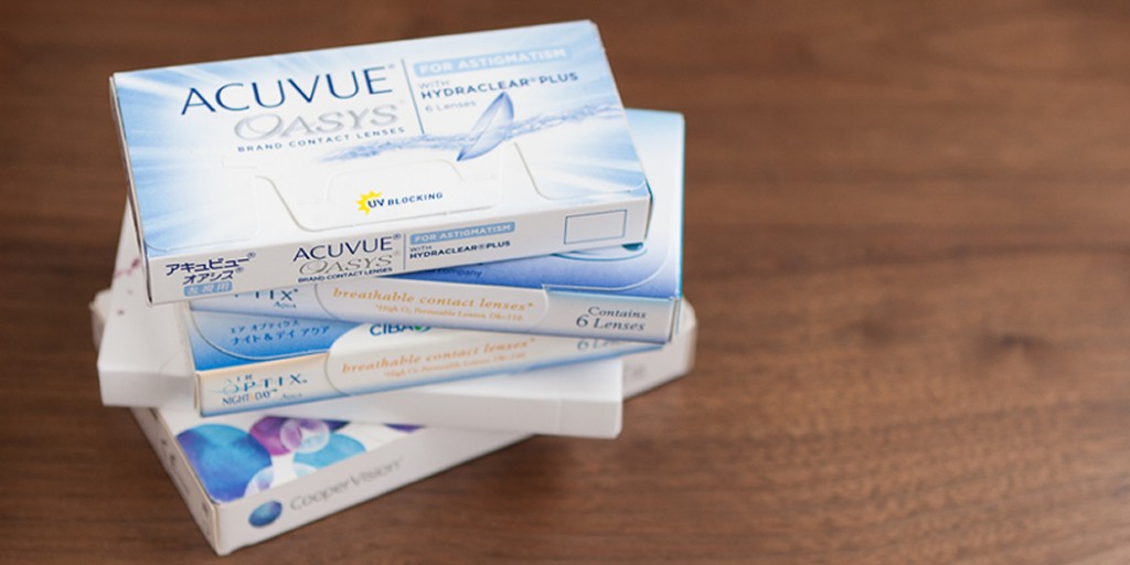 A pile of contact lens boxes on a wooden table