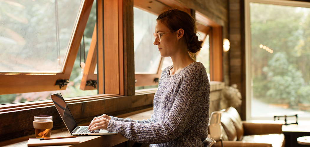 Woman wearing glasses using laptop in cabin