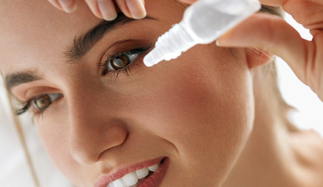 woman removes contact lenses and flushes her eyes with artificial tears or lubricating drops after water gets in her contacts when swimming