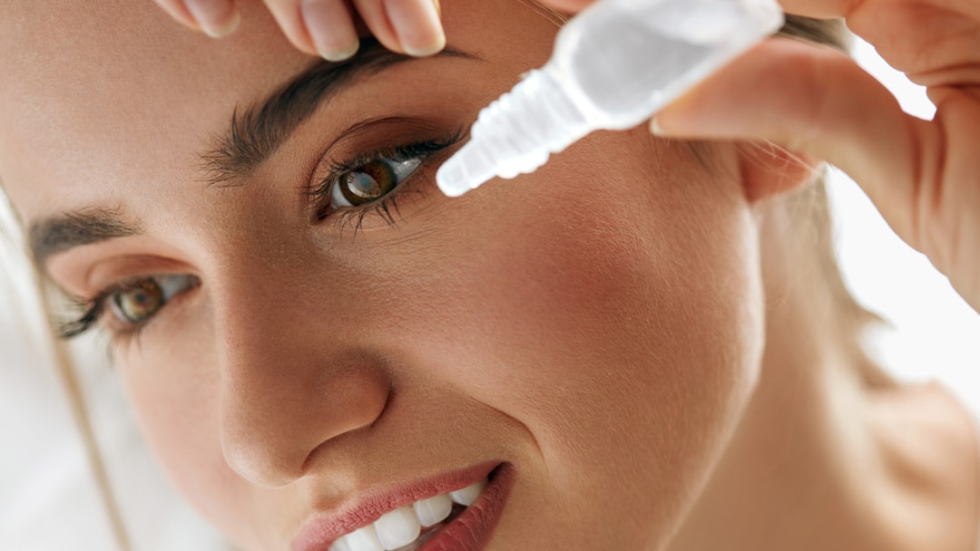 woman removes contact lenses and flushes her eyes with artificial tears or lubricating drops after water gets in her contacts when swimming