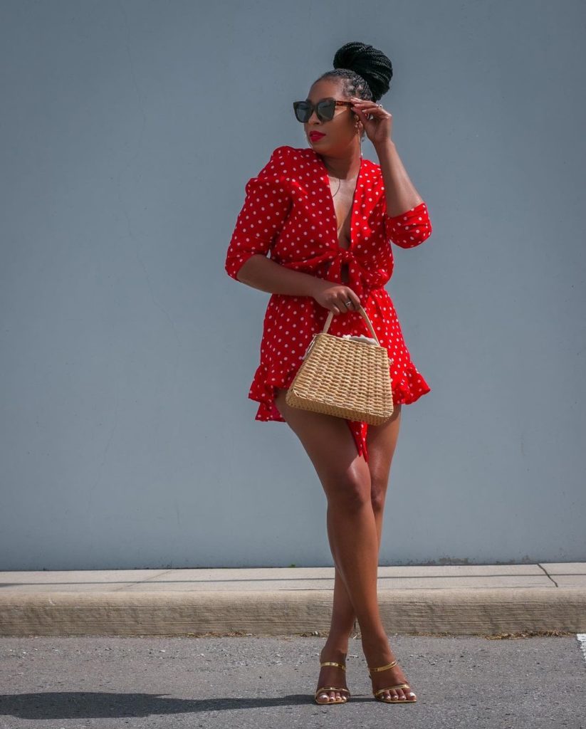 woman in red polka dot dress wearing sunglasses and holding a wicker handbag