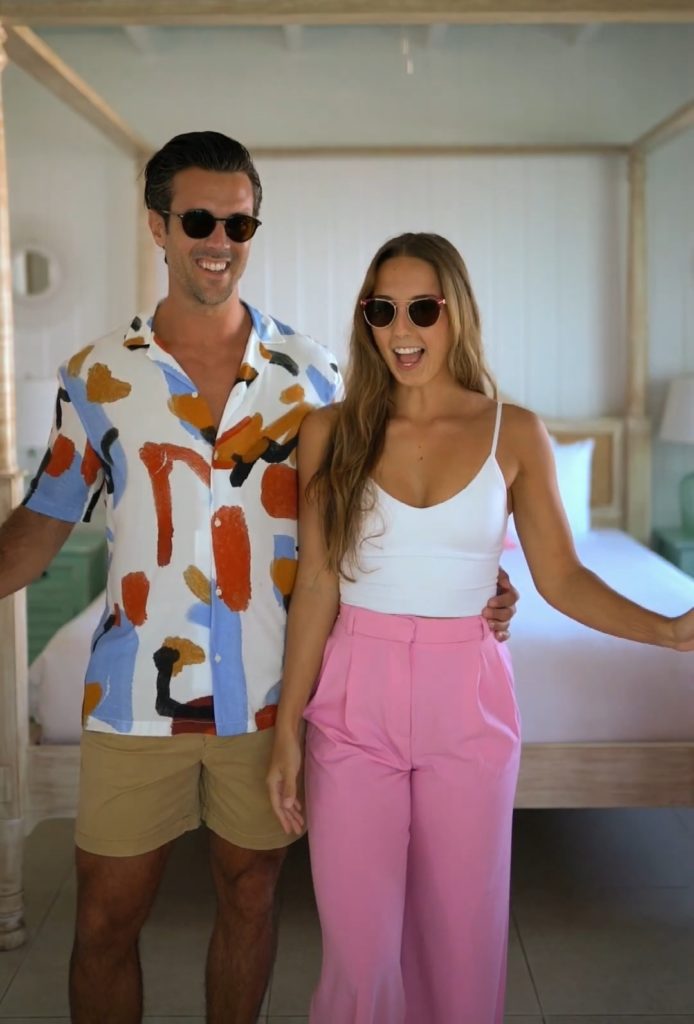 a man and a woman standing in a doorway both wearing sunglasses and summer outfits