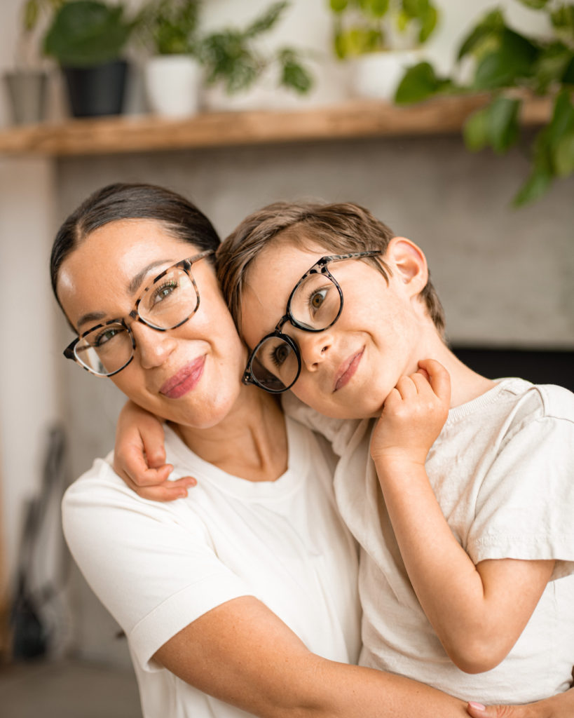 woman and boy cuddling wearing tortoiseshell glasses and white shirts